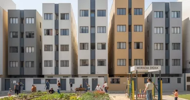 Famílias em frente a um conjunto habitacional popular em zona urbana central.