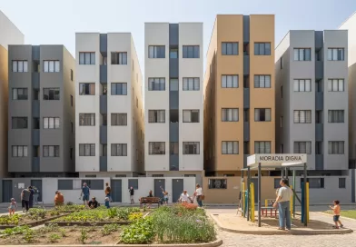 Famílias em frente a um conjunto habitacional popular em zona urbana central.