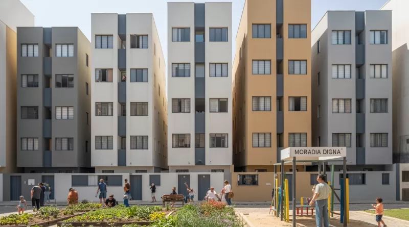 Famílias em frente a um conjunto habitacional popular em zona urbana central.
